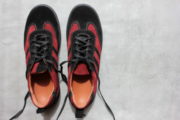 Pair of orthopedic sports shoes on a gray concrete background with copy space. Close-up of suede burgundy orthopedic sneakers from above
