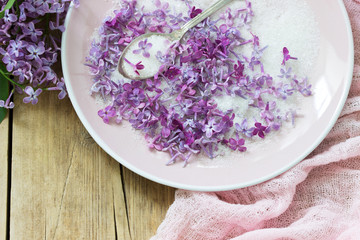 Lilac flowers with sugar, lilac and pink napkin on a wooden background. Rustic style.