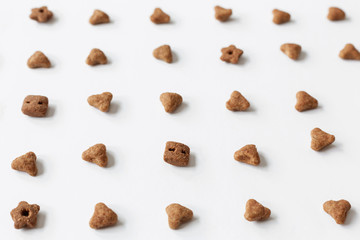 Background of cat dry food. Minimalistic white flat. Domestic kitty care. Natural backdrop