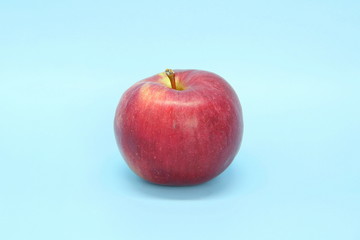 Red yellow apple on a blue background. Juicy ripe beautiful fruit.