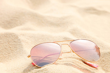 Pink sunglasses lie on the sea sand.