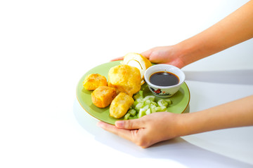 mpek-mpek or pempek. fish and tapioca served on a green plate with rich sweet and sour sauce called kuah cuka or vinegar sauce. Isolated on white background