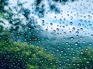 Raindrops on car window with blurred nature forest in the background