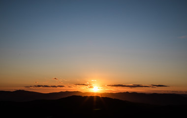 Fototapeta na wymiar Beautiful sunset with sun rays with hills silhouette