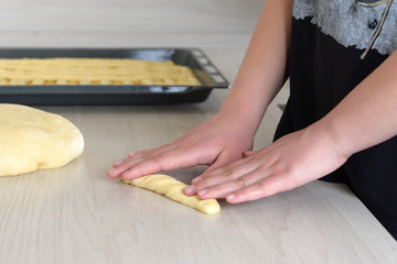 A woman cooks a pie with her own hands. Making a cake at home. Women's hands roll out the dough