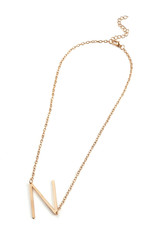 Subject shot of a golden chain with a pendant in the shape of a letter N. The fashion necklace is...