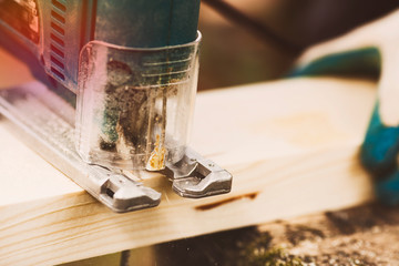 Carpenter working with hacksaw (jigsaw) on wooden plank in outdoor. Hands in construction gloves. Woodworking and craftsmanship concept. Close up. Space for a text.