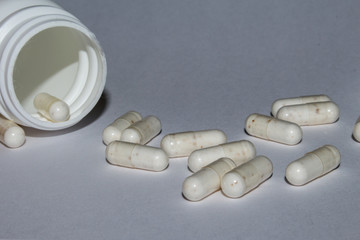 white tablets in capsules scattered from a can