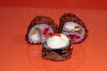 Sushi on the orange table is reflected. Three hot sushi. Japanese food on a creative background.