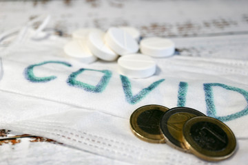 cost of healthcare big white round tablets with medical mask with inscription covid and euro coins