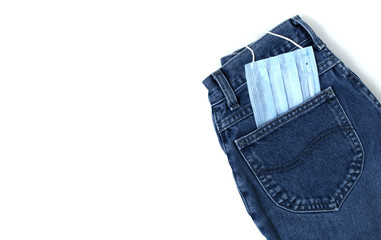 Classic blue jeans on the white background. Medical mask in the pocket. Pandemic concept. Copy space. Place for text and design. Top view. Flat layout