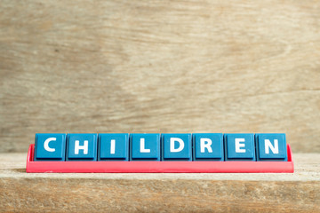 Tile letter on red rack in word children on wood background