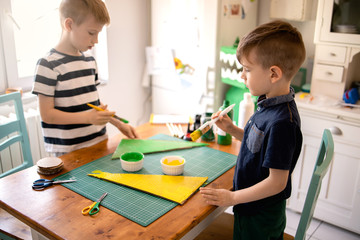 Brothers painting a cardboard dinosaur costume
