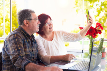 Fototapeta premium Mature couple in quarantine due to coronavirus on fathers day, video call with their children. communication and technology concept.