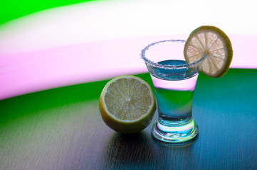 shot tequila with salt, lime slice and lime on the background of colored stripes