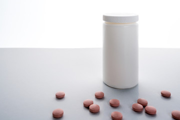 Blank prescription bottle isolated on white background with red pills laying infront.