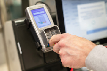 Man paying at the self-service counter entering credit card pin code for security password in credit card swipe machine. shopping time