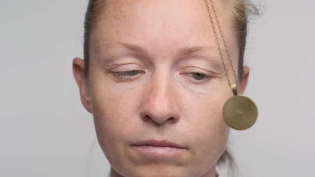 Woman falls asleep looking at pendulum in hypnosis session. pendant on chain sways in face of businesswoman in seance.