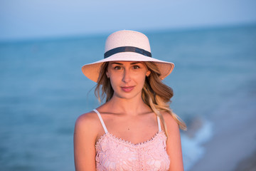 girl with a ball on the beach. young woman in hat on the beach. young woman in pink dress on the beach. 
Holidays at sea.