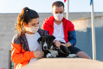 young couple wearing a protective mask is walking alone with a dog outdoors because of the corona virus pandemic covid-19
