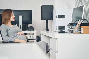 Attractive pregnant lady working in modern office