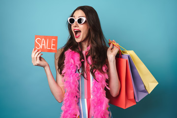 Image of delighted woman in boa holding sale card and shopping bags