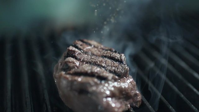 chef adds pepper to the roasting beef steak