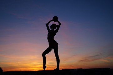 dancer in the dance does the splits in the air against the sunset.