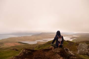 Young hiker woman sitting on the top of the hill in Scotland
