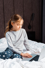 kid using laptop with e-learning in bedroom