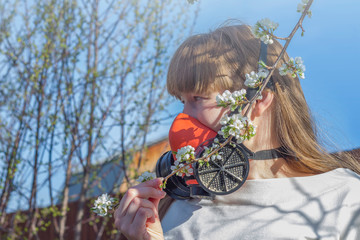 Portrait of young woman in respirator gas mask against the blossoming trees during coronavirus pandemic. The concept of air pollution or protection from pollen and flowering allergy in spring