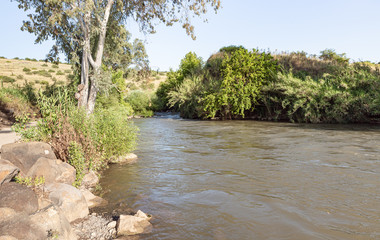 Fototapeta na wymiar The wide, full-flowing Jordan River flows in the Golan Heights in northern Israel