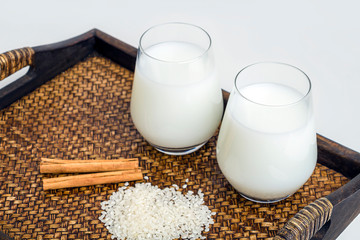 Two glass of vegatarian rice milk and rice grains served on a tray.  An invigorating healthy...