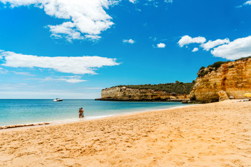 Fototapeta na wymiar Young couple enjoying beautiful, sandy beach with cliffs in Algarve, Portugal