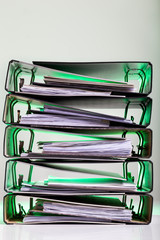 Stack of files with archived paperwork in green light.