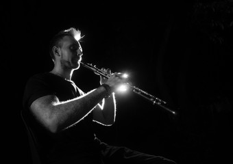 Musician playing flute on black background - obrazy, fototapety, plakaty