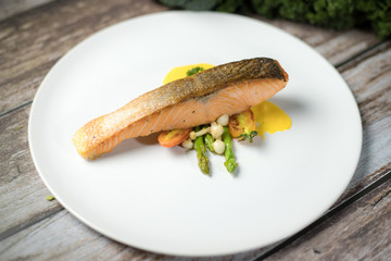 Salmon Steak.Grilled salmon with yellow cream sauce and asparagus on a white plate