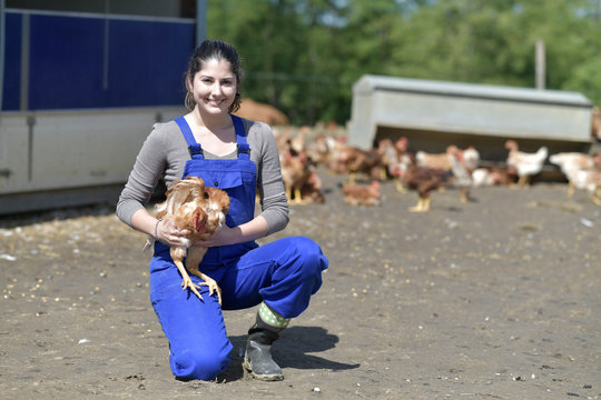 Smiling young farmer holding hen