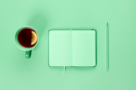 Tea Cup And Fancy Notebook With Empty Or Blank Page On Desk From Above. Copy Space