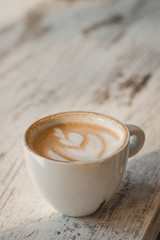 A small white cup of coffee stands on table in coffee shop. Fragrant pressure. Background. Space for text. 