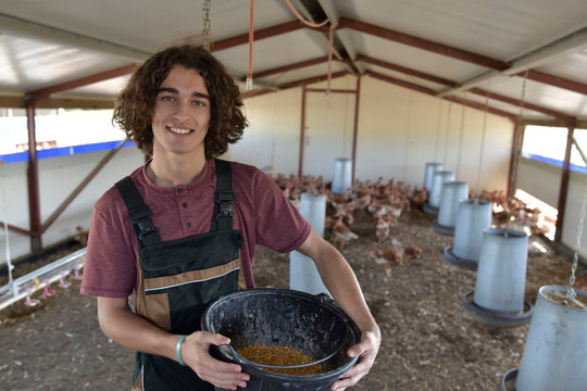 Smiling young farmer standing in henhouse