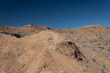 Hard packed mountain path along a ridge in the New Mexico desert, deep blue sky, road less traveled, horizontal aspect
