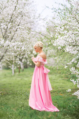 beautiful girl in a pink dress walks in a blooming garden in spring.