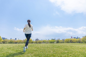 自然豊かな公園をランニングする若い女性