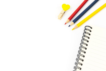 color pencils and notebooks and  clothespins placed on a white background in the home studio. This concept is used as an illustration for education idea