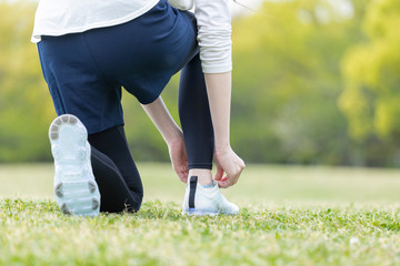 靴紐を結び運動の準備をする若い女性