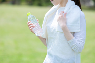 ペットボトルを持ち佇む運動着姿の若い女性