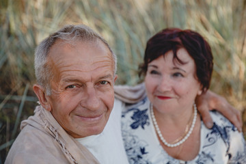An old married couple on a summer walk in the field. In focus close up of the spouse's face