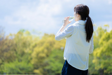 ペットボトルを持ち佇む運動着姿の若い女性