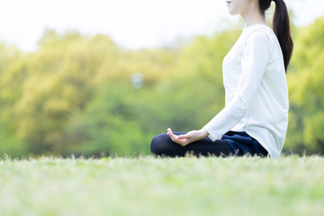 Fototapeta premium 緑豊かな公園でヨガのポーズをとる若い女性